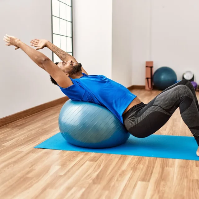 Mann macht eine Rückenübung auf einem Gymnastikball