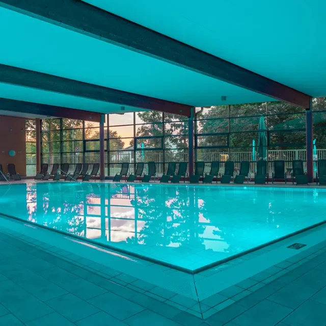 Hallenbad mit großem Schwimmbecken und Liegestühlen
